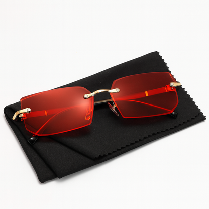 Gafas de sol sin marco con lentes rojas brillantes y detalles dorados, accesorio perfecto para el verano.